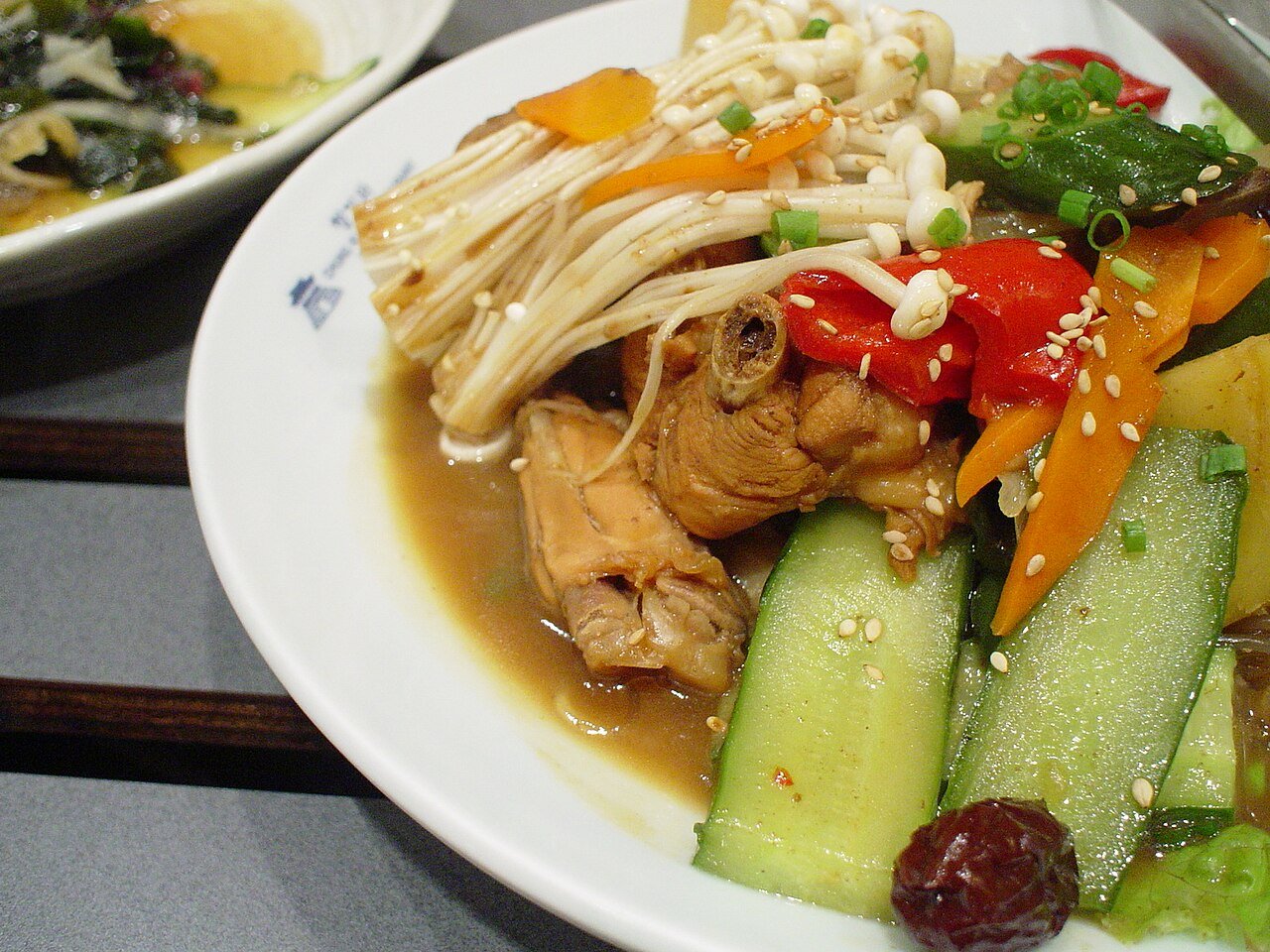 A large pot of Andong jjimdak with braised chicken pieces, potato, carrot and glass noodles in a dark soy sauce