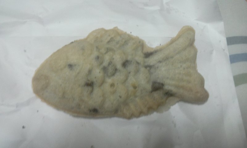 A single whole bungeoppang on a cloth, showing the golden-brown fish-shaped exterior with a clear scale pattern from the mold