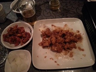 A table set with a plate of Korean fried chicken next to bottles of beer