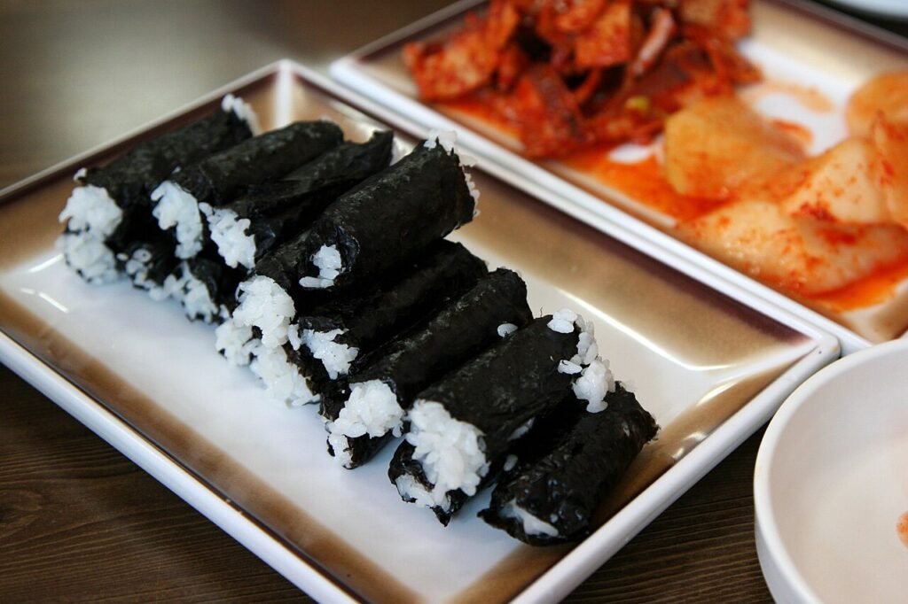 A plate of chungmu gimbap: bare rice rolls in seaweed served with spicy squid and radish kimchi