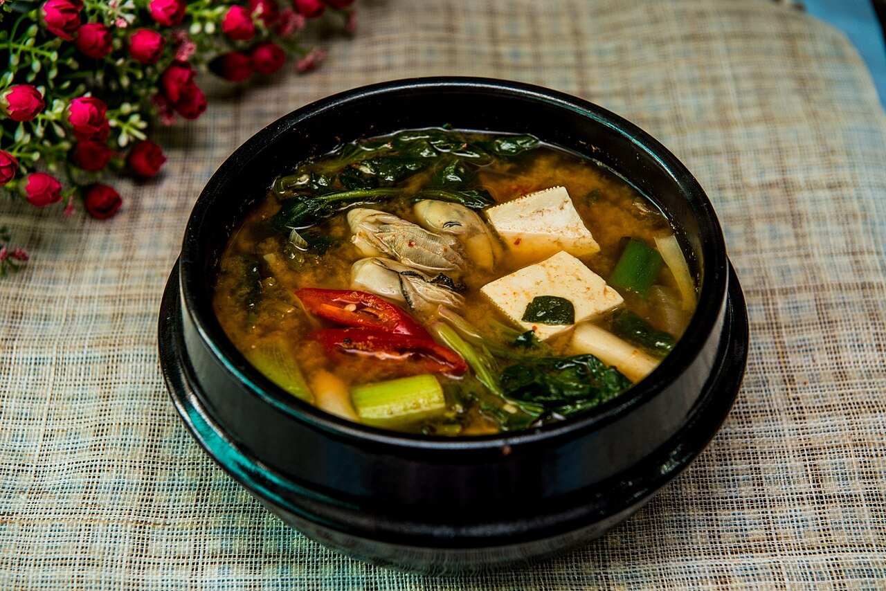 A bubbling pot of doenjang jjigae with tofu, zucchini, and potato