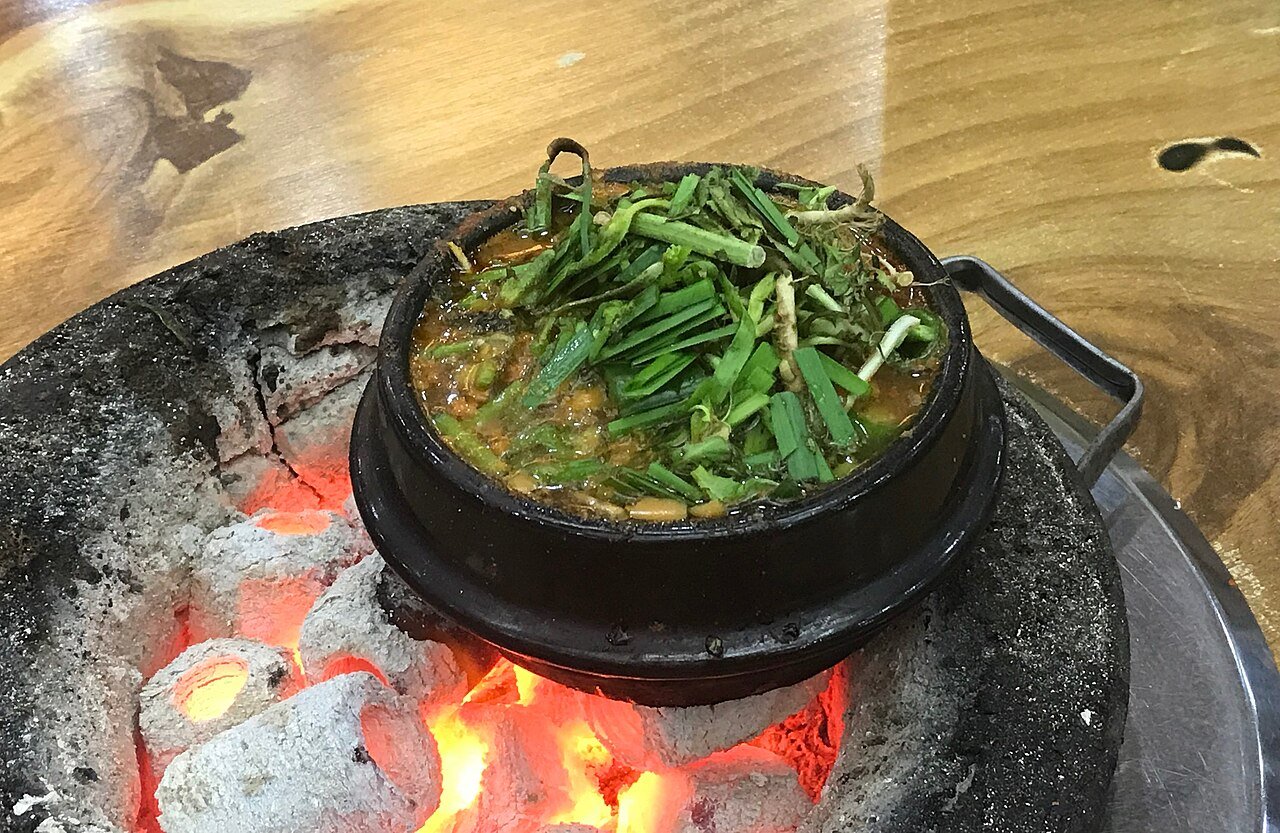 Doenjang jjigae served in an earthenware pot alongside rice and banchan