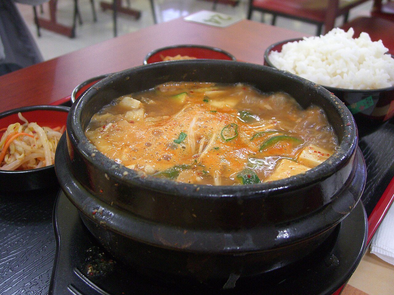 A close view of doenjang jjigae broth with visible soybean paste and vegetables