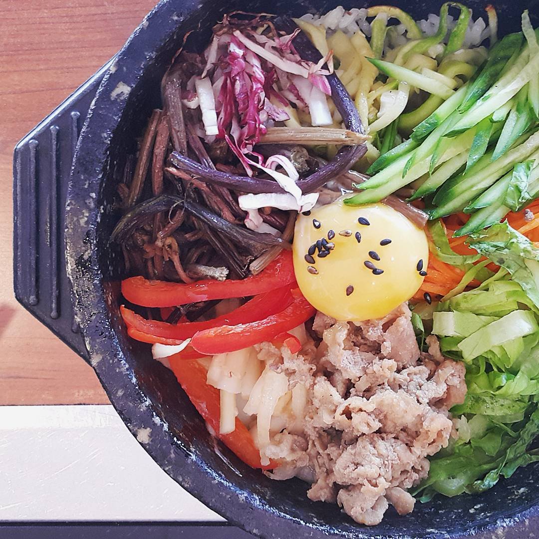 Close-up of dolsot bibimbap in a stone bowl with rice pressed against the hot sides