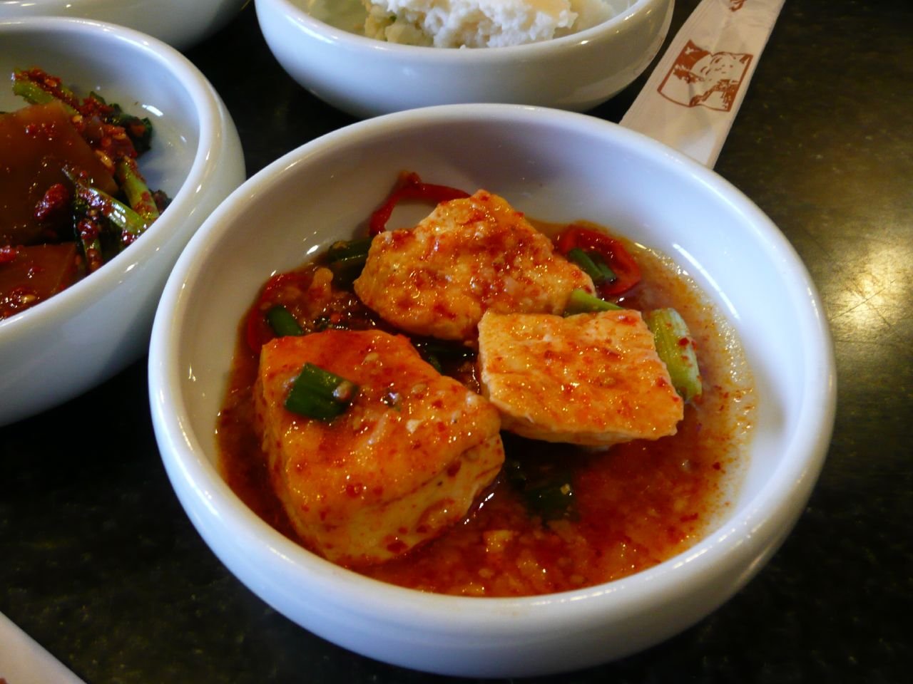 Sliced braised tofu arranged on a plate with a soy-based glaze and scallions
