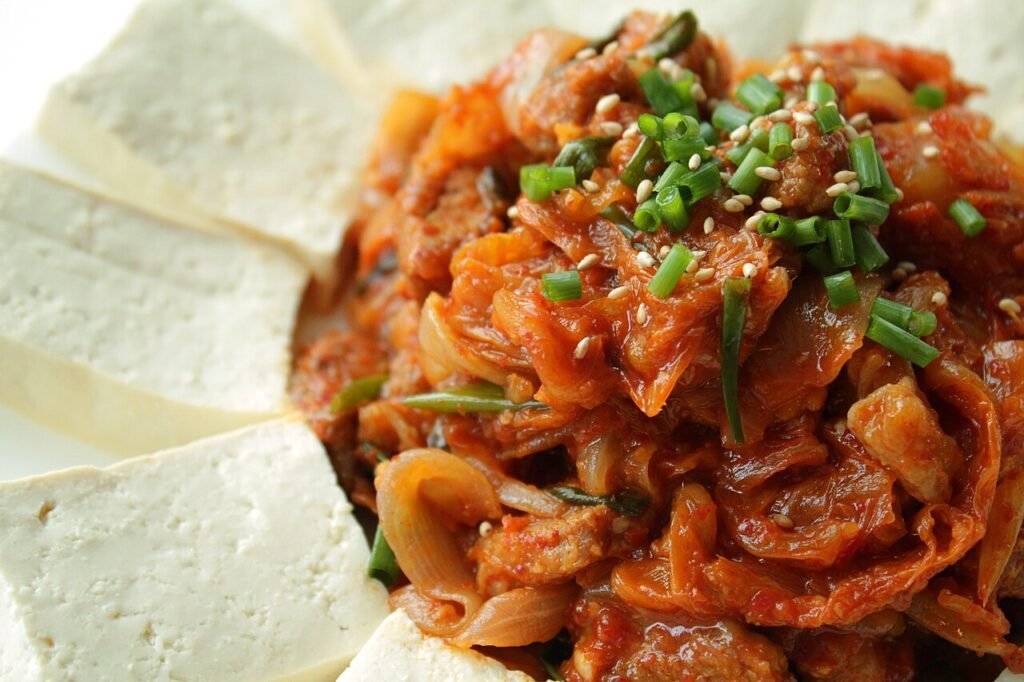 Dubu kimchi served on a white plate: white tofu slabs arranged around a mound of red stir-fried kimchi