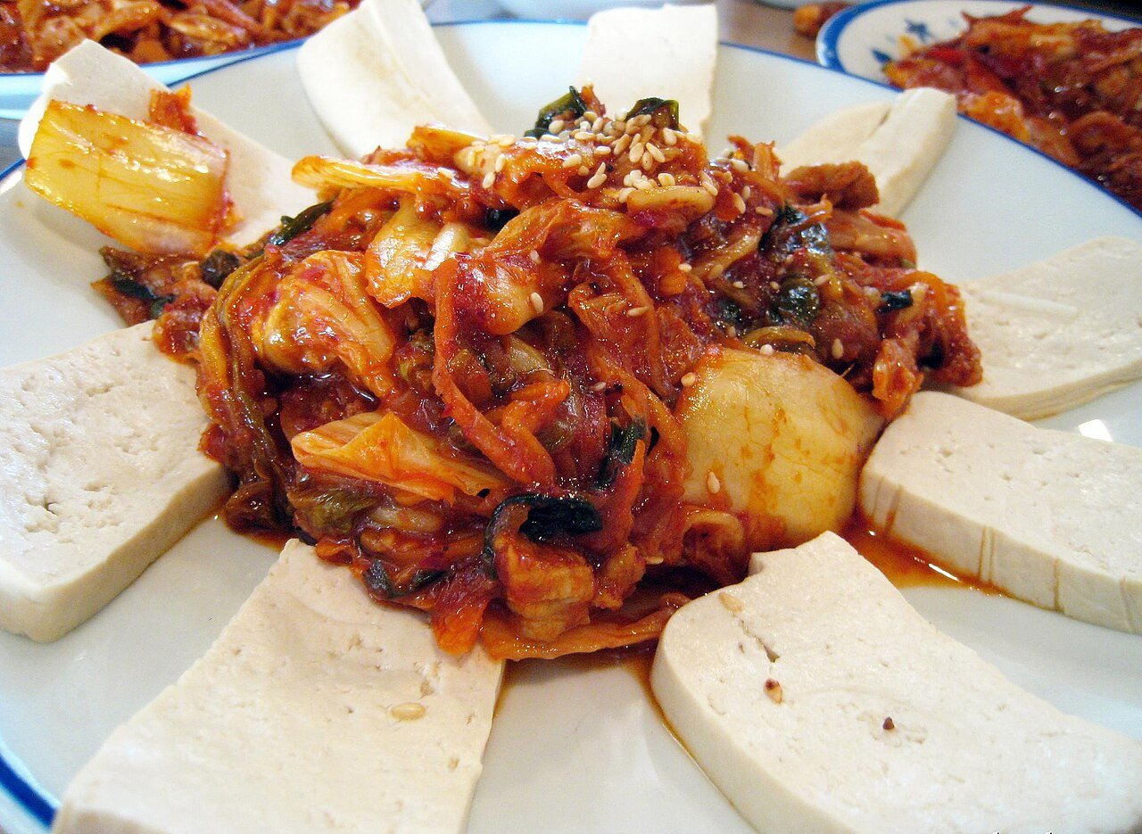 A plate of dubu kimchi with sliced tofu ringing stir-fried kimchi and pork