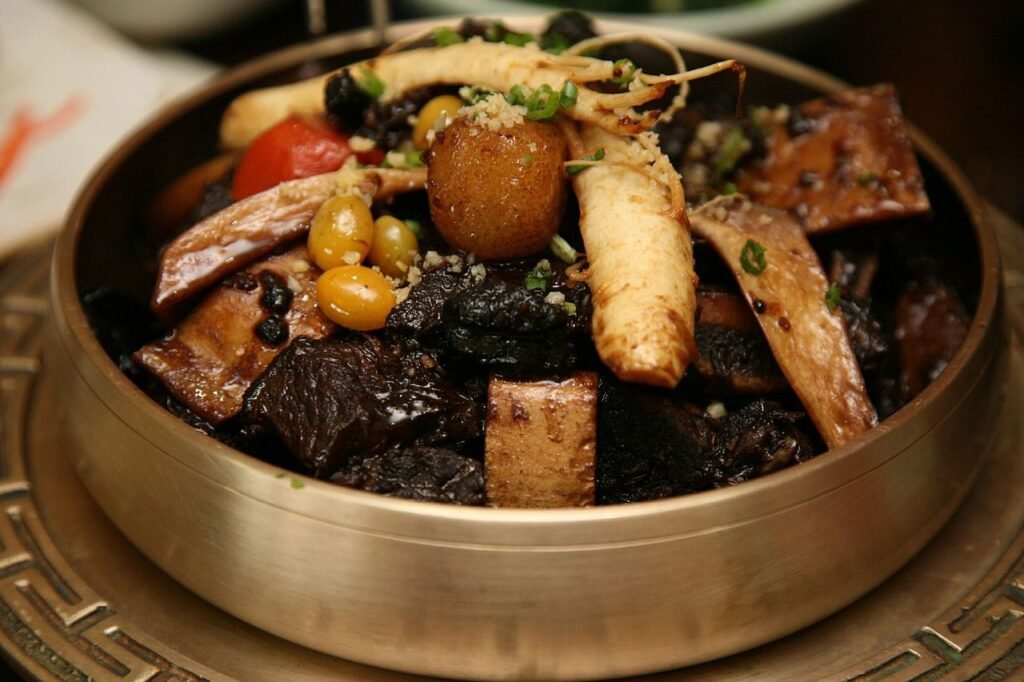 A bowl of galbijjim, braised beef short ribs with carrot, radish and chestnut in a dark, glossy soy sauce