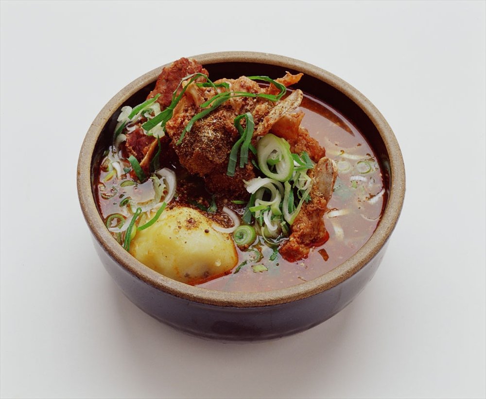 A pot of gamjatang, pork backbone soup with potatoes and napa cabbage leaves