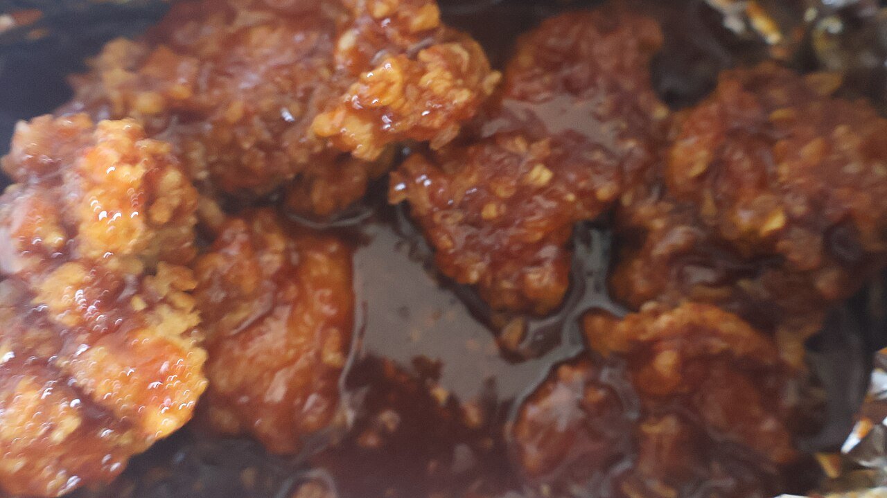 Fried chicken pieces coated in a glossy red sweet-spicy gochujang glaze