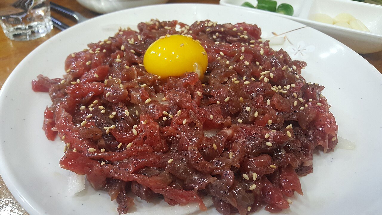 A plate of yukhoe, raw seasoned beef strips topped with a raw egg yolk, served at Gwangjang Market in Seoul