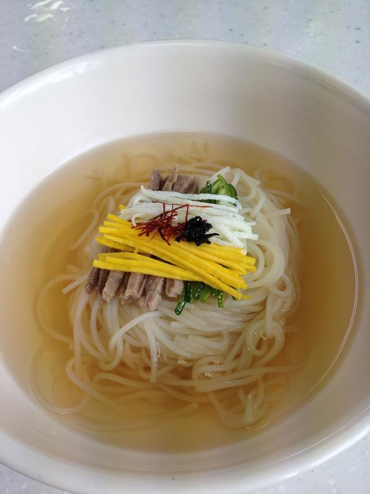 A bowl of janchi guksu, thin wheat noodles in broth topped with julienned egg and vegetables