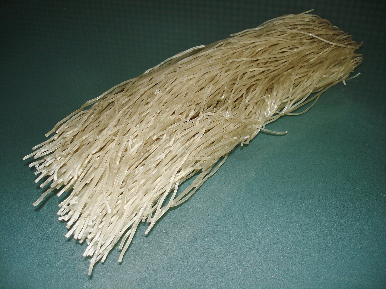 A coiled bundle of dry, uncooked Korean sweet potato glass noodles (dangmyeon)