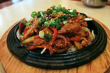 A close serving of spicy stir-fried pork glazed in red gochujang sauce, served with rice