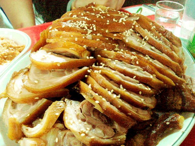 A close-up plate of jokbal slices next to lettuce leaves and a small bowl of saeujeot