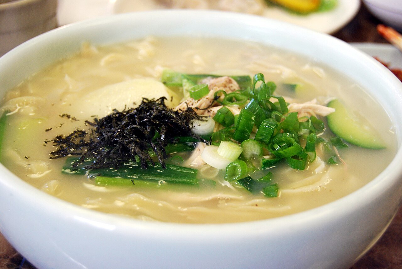 A bowl of kalguksu, Korean knife-cut wheat noodles in a light broth with zucchini