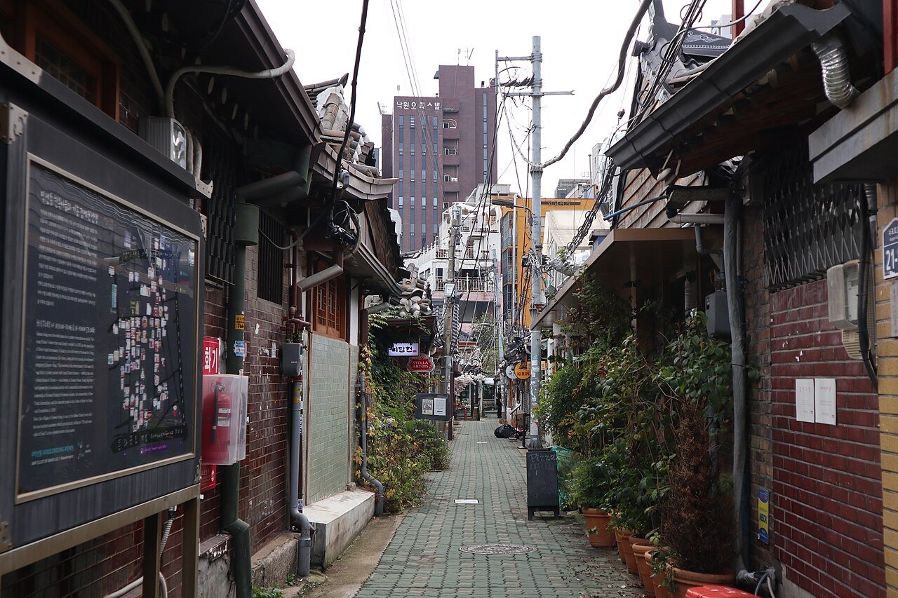 A narrow brick-paved alley in Ikseon-dong lined with low tiled-roof hanok houses converted into restaurants