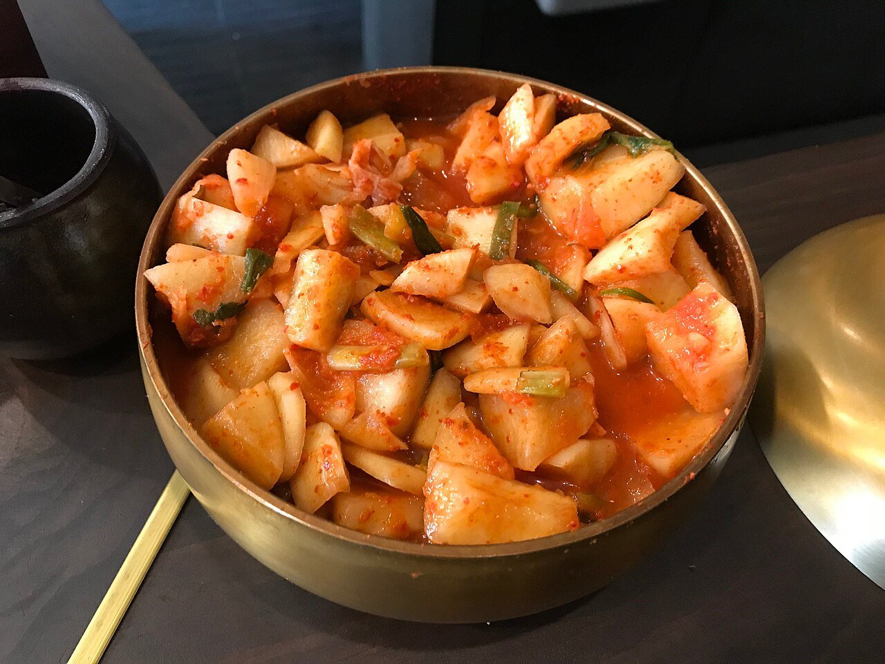 Close-up of radish kimchi cubes glistening with red seasoning paste in a container
