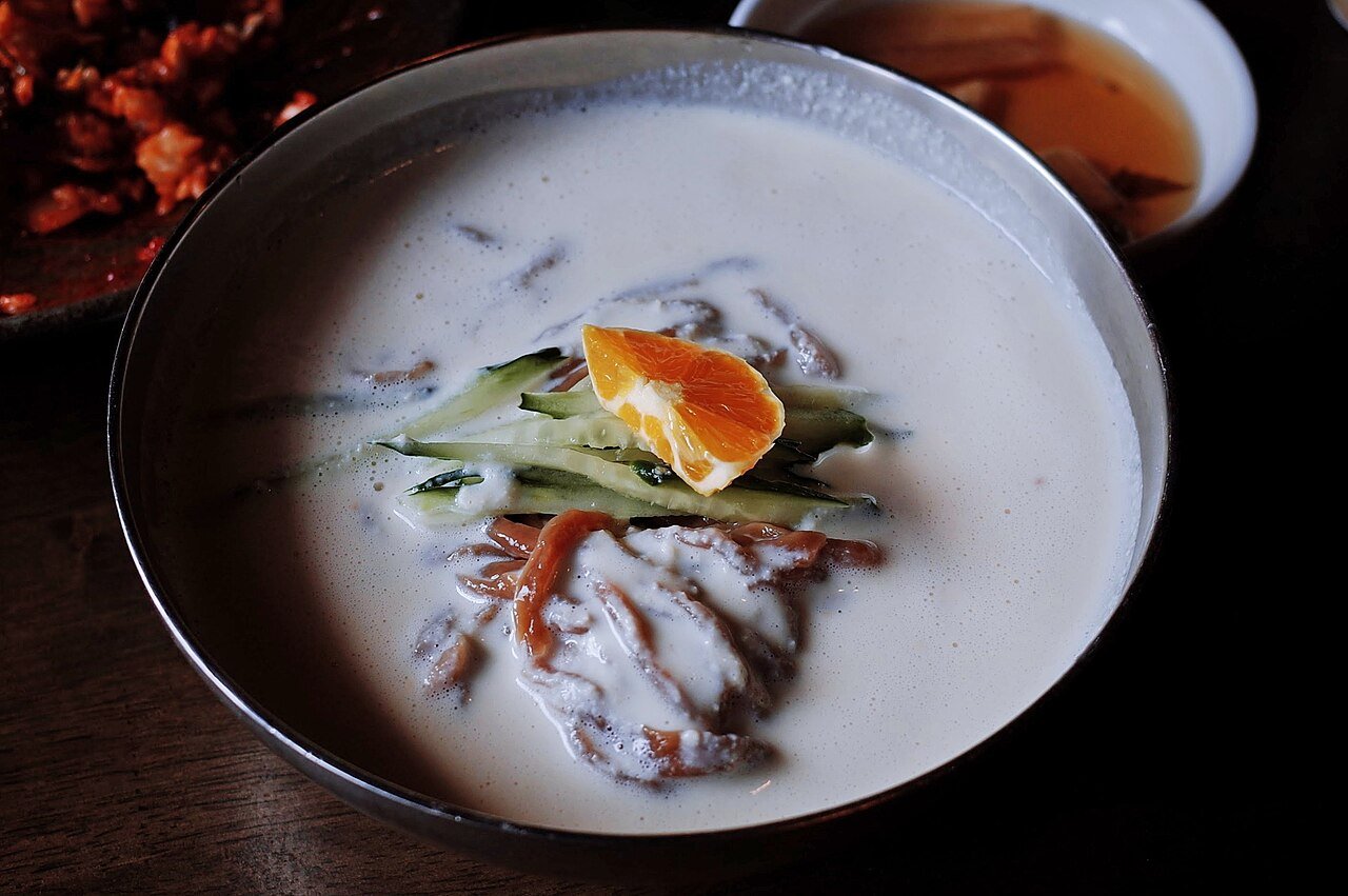 A bowl of kongguksu, chilled white soy milk noodle soup, topped with cucumber and ice