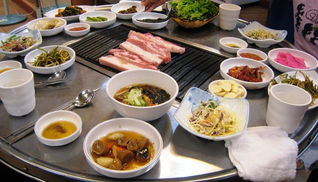 Thick-cut pork belly slices grilling on a tabletop Korean barbecue grill