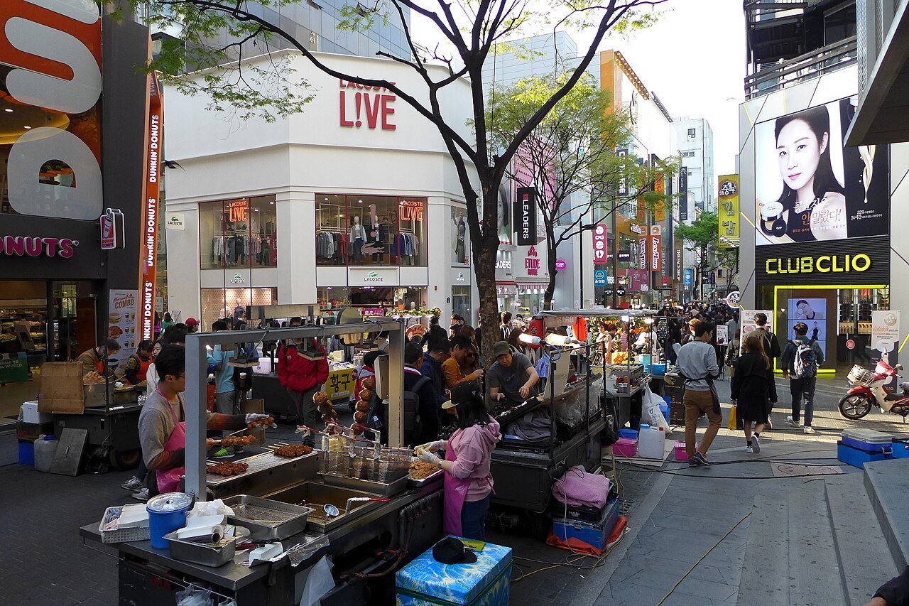 Street food stalls and hawkers along a busy pedestrian street in Myeongdong, Seoul