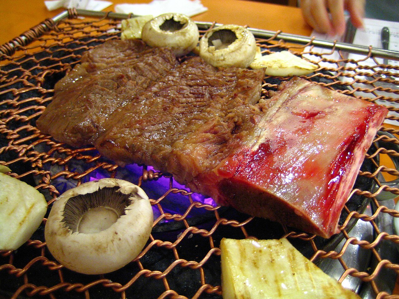 Grilled Korean short ribs on a tabletop grill, dark from caramelized marinade