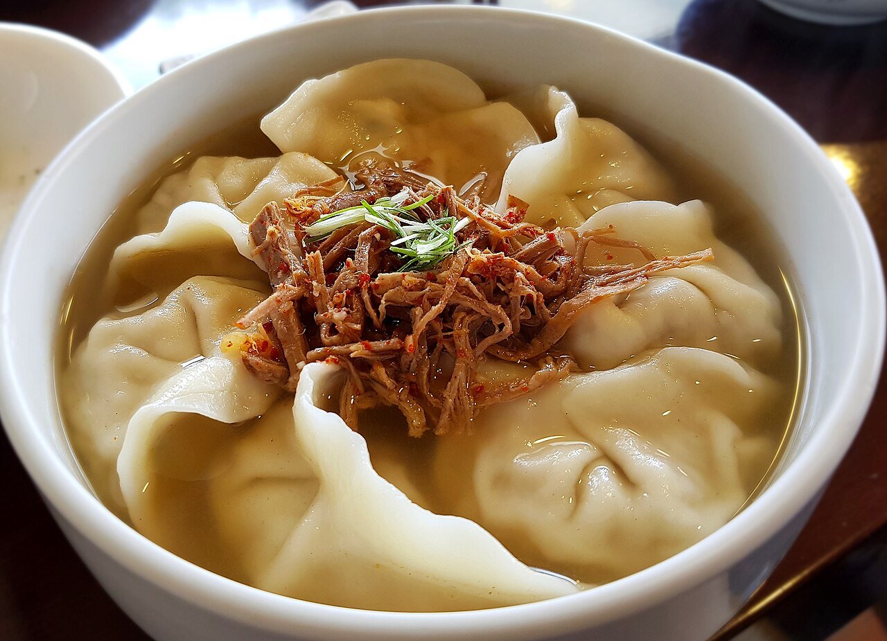 A bowl of manduguk with Korean dumplings in a clear broth, photographed at a restaurant in Seoul