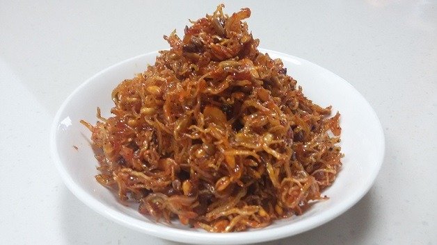 A bowl of Korean stir-fried dried anchovies coated in a glossy dark sauce