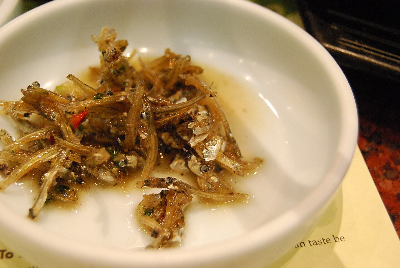 Stir-fried anchovies served in a small white dish as a Korean side dish