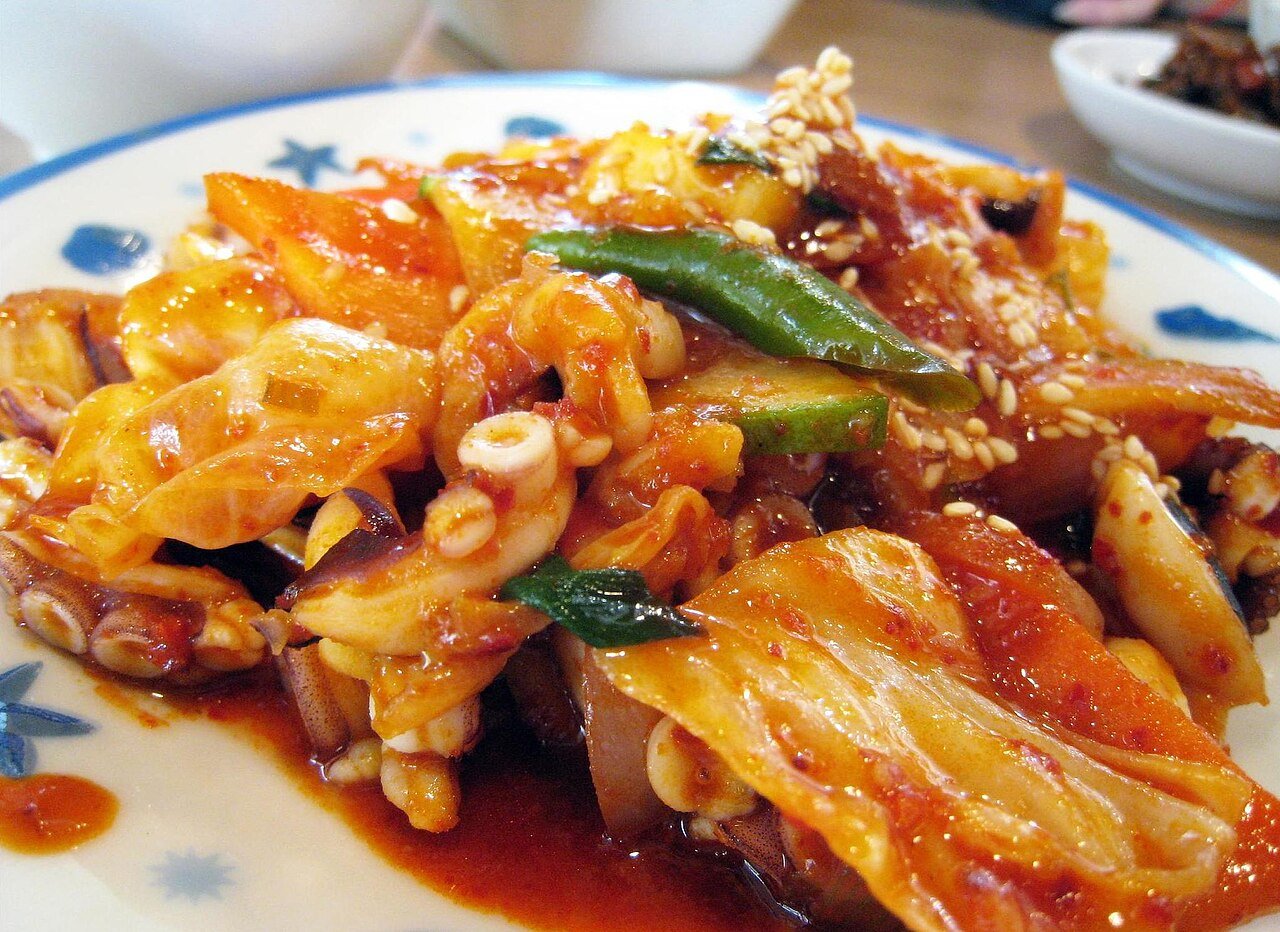 Close view of stir-fried octopus pieces coated in red gochujang sauce