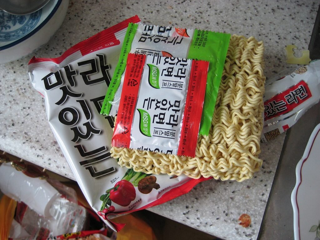 A pot of Korean instant ramyeon in red broth with noodles and a soft egg on top