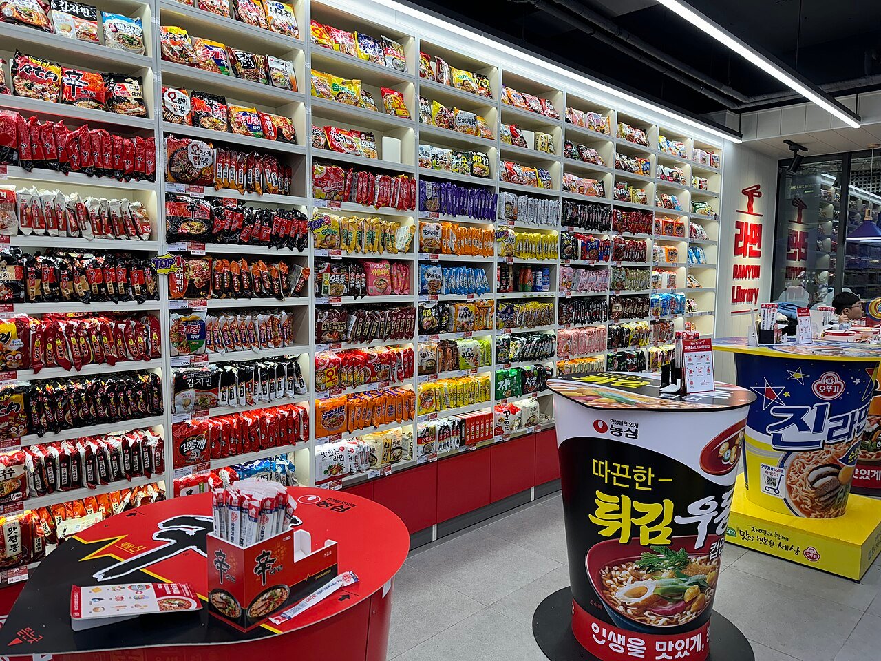 A 24-hour Korean convenience store sign advertising ramyeon, lit up at night