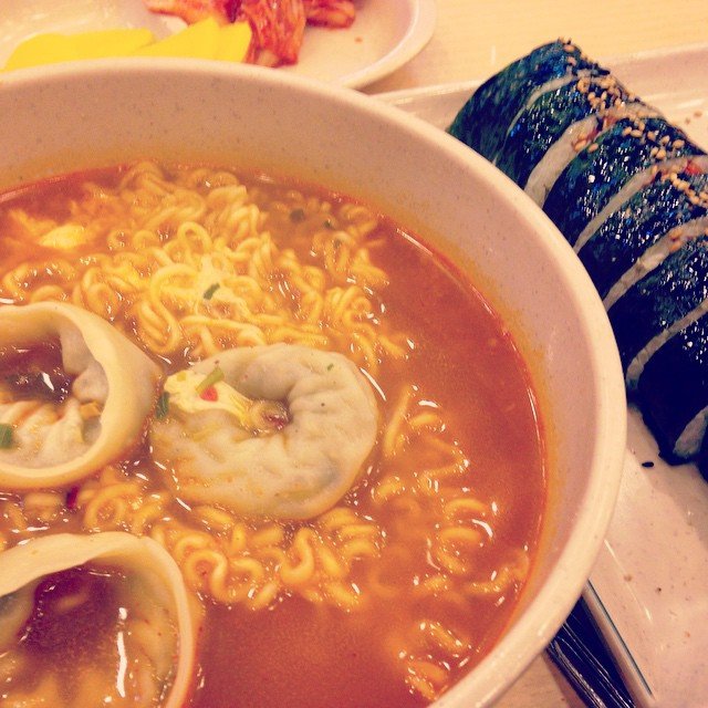 Ramyeon with dumplings added to the broth, served alongside a plate of sliced kimbap