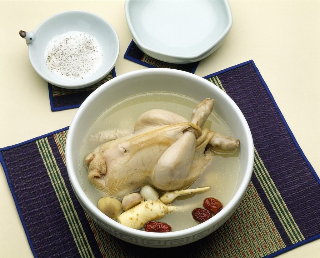A whole young chicken stuffed with rice, floating in a milky white ginseng broth in a stone pot