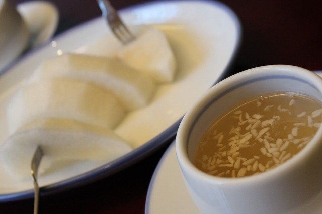 A glass of pale golden sikhye, Korean sweet rice drink, served cold