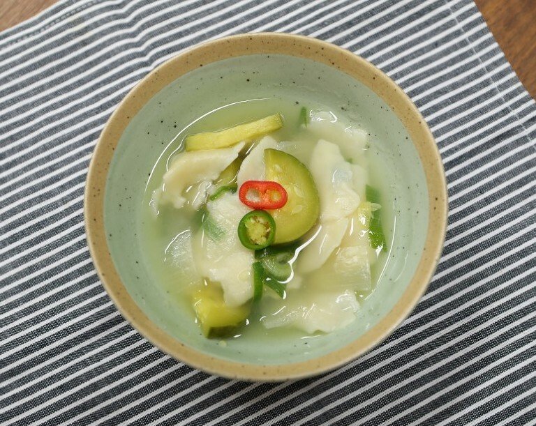 A bowl of sujebi, hand-torn dough pieces in a light broth with vegetables