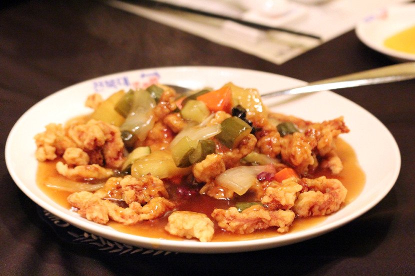 Korean Chinese tangsuyuk served on a white plate with the sweet and sour sauce poured over the fried pork