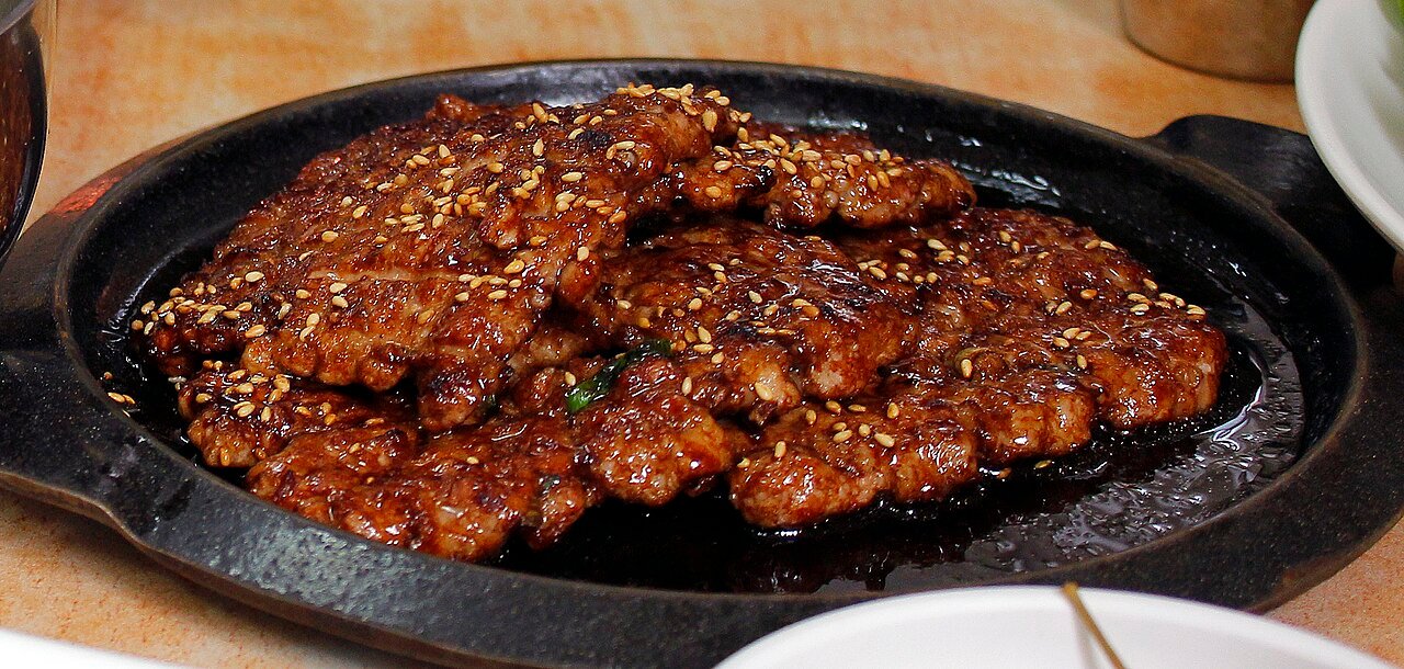 A restaurant plate of tteok-galbi patties, thick and oval, grill marks visible on the surface