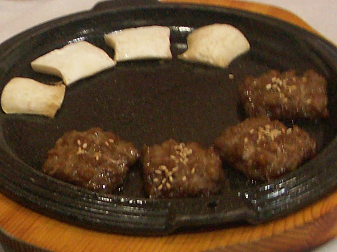Close-up of a single tteok-galbi patty showing its dense, chewy interior