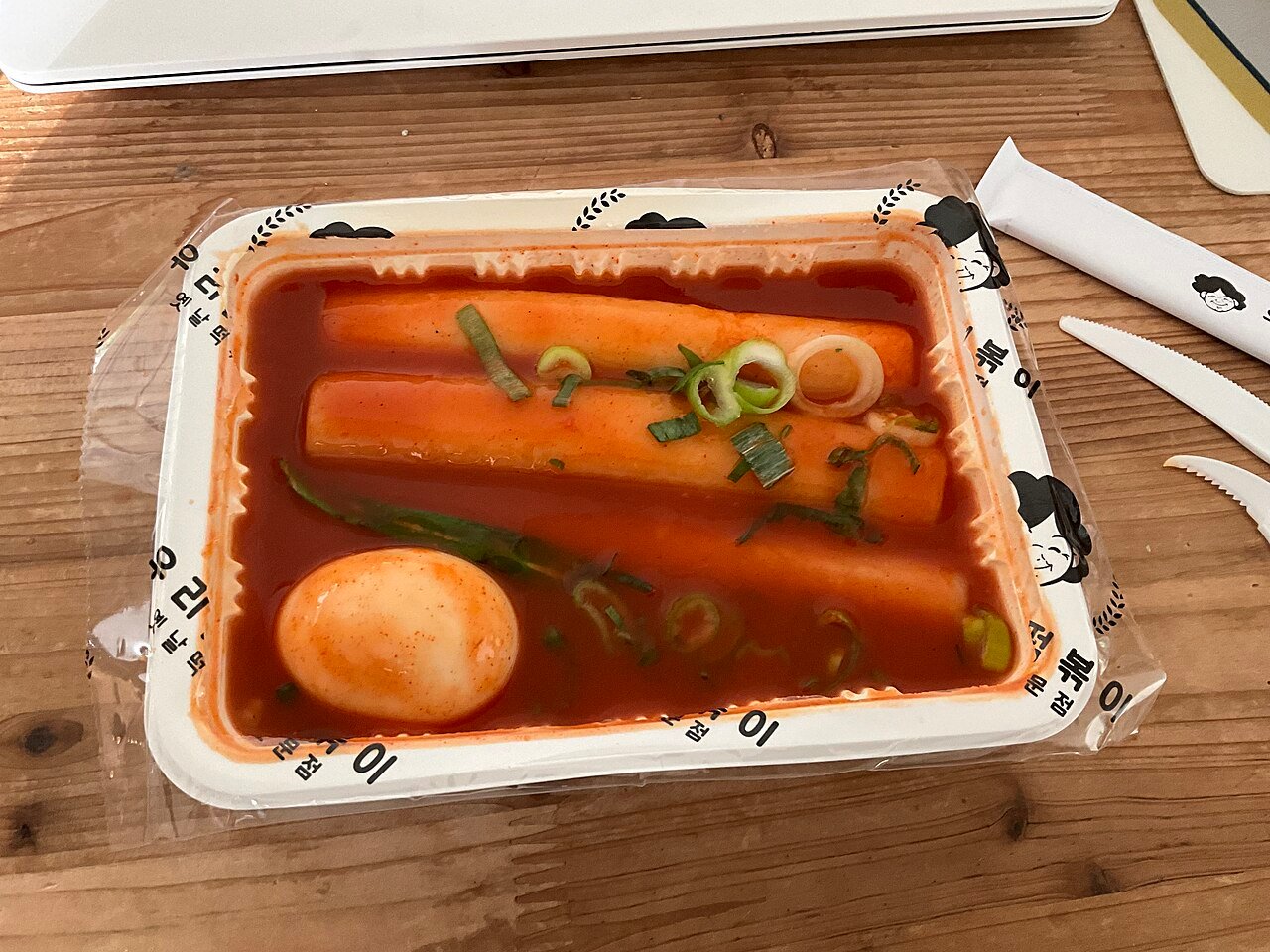 Thick garae-tteok rice cake cylinders in red tteokbokki sauce, served in a shallow metal dish