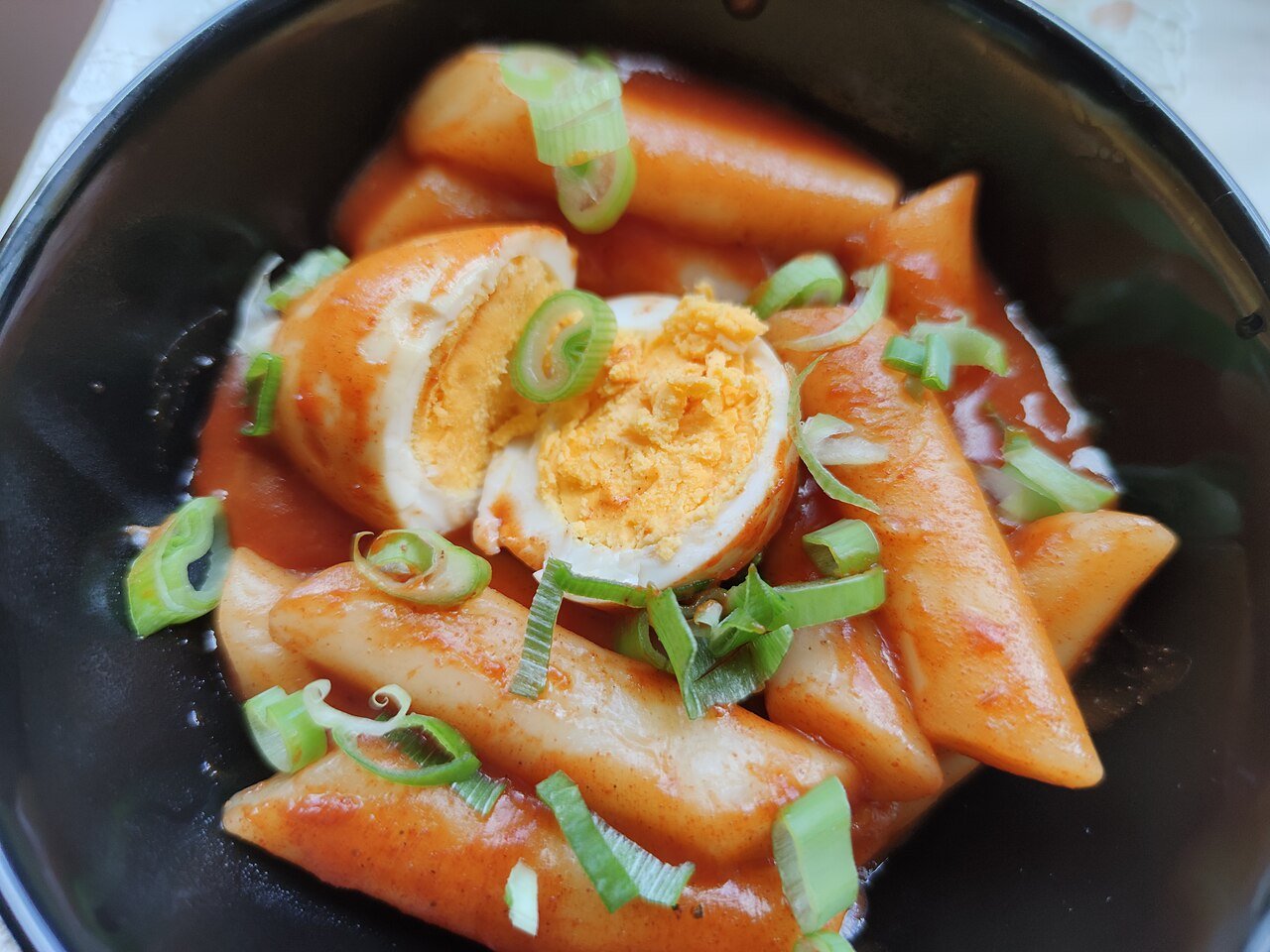 Finished tteokbokki being served from the pan, the sauce reduced until it clings to each rice cake