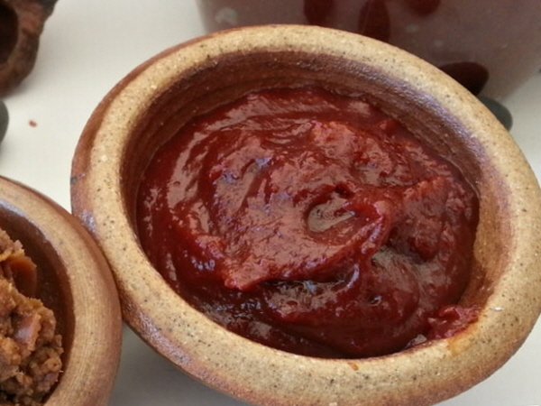 Thick dark red Korean fermented chili paste, gochujang, in an open tub