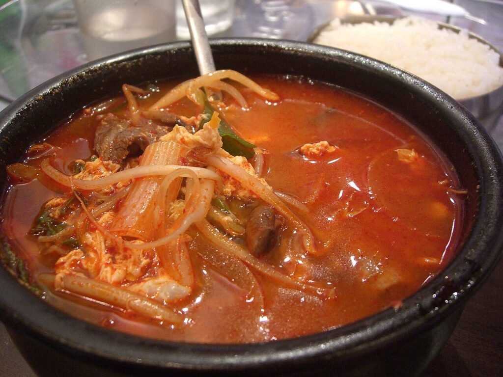 A bowl of red, spicy yukgaejang with shredded beef, scallions, and bean sprouts