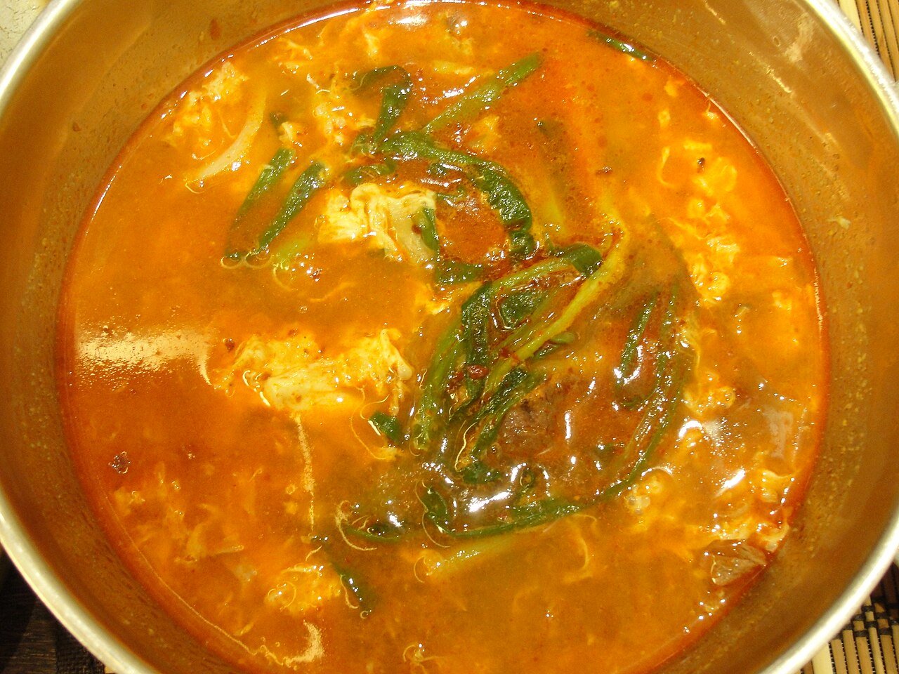 A bowl of yukgaejang with rice on the side, photographed at a restaurant table