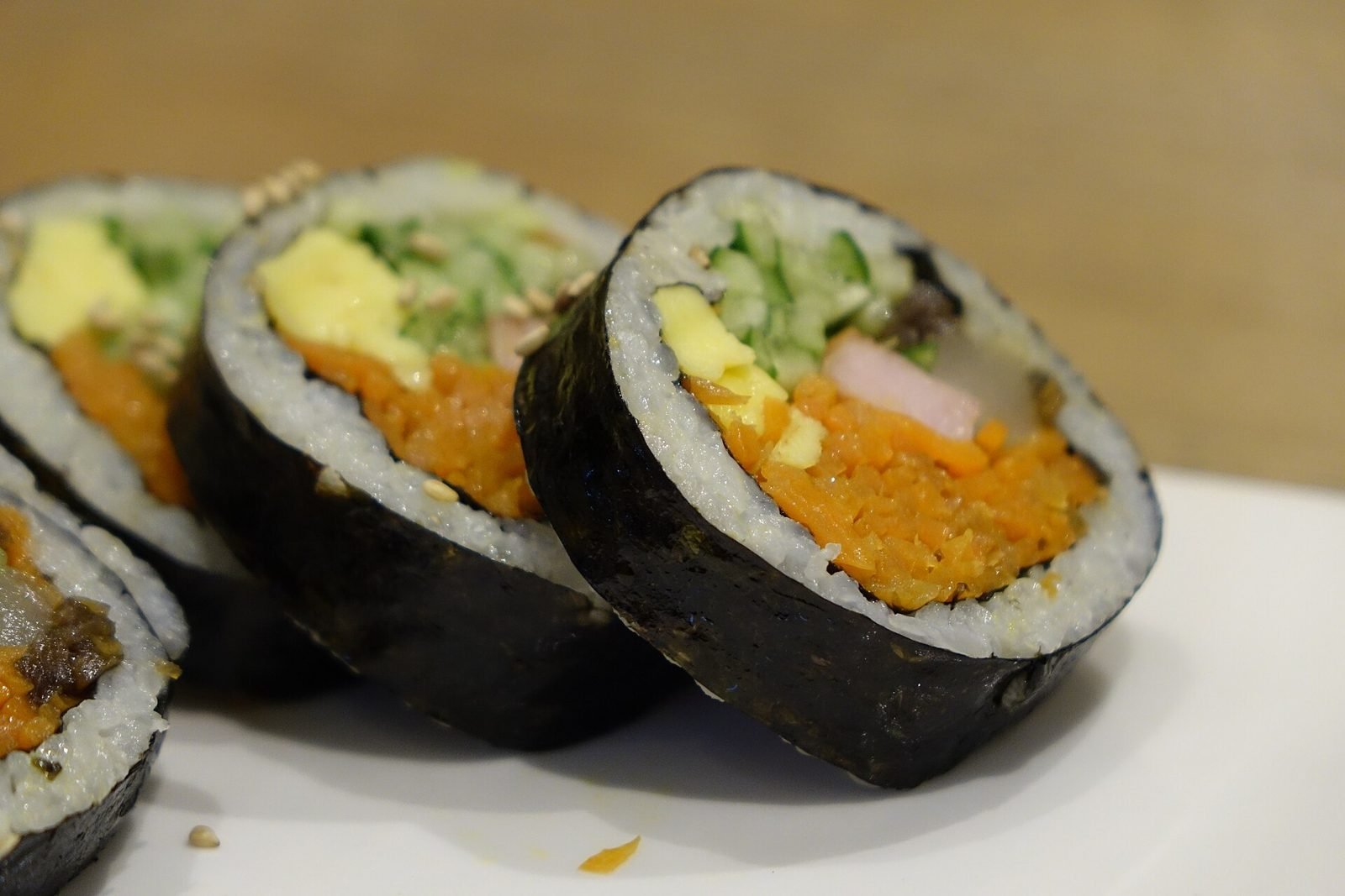 Close-up of kimbap slices with carrot, egg and ham visible in cross-section