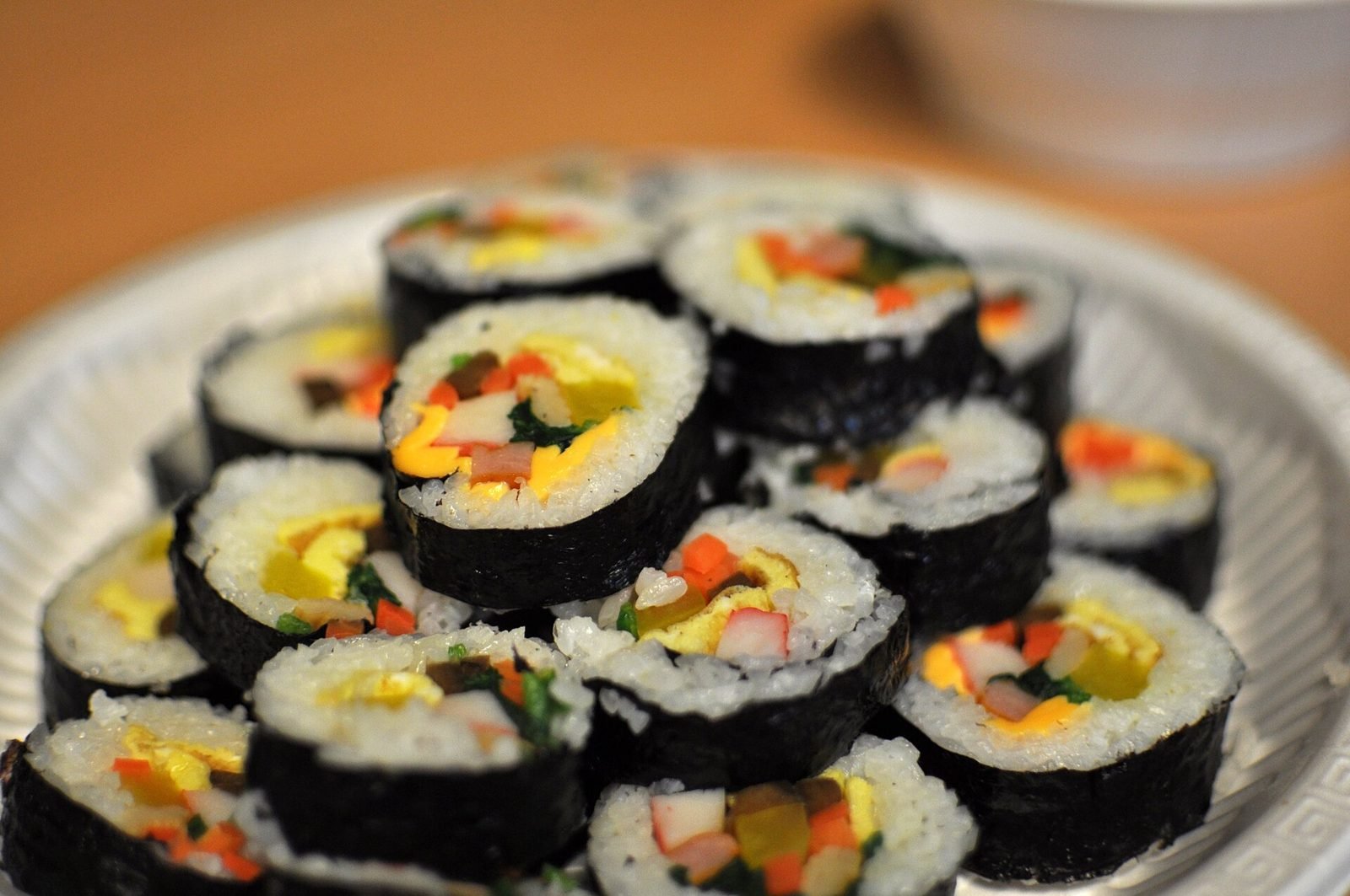 Sliced kimbap rolls stacked on a plate showing colorful fillings
