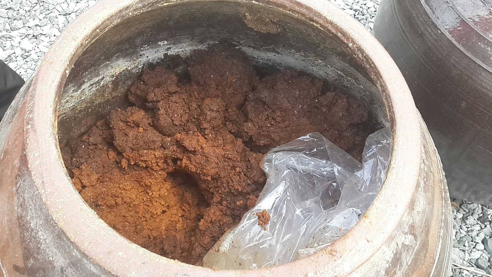 Open clay crock filled with brown fermented soybean paste in Gangjin, South Korea