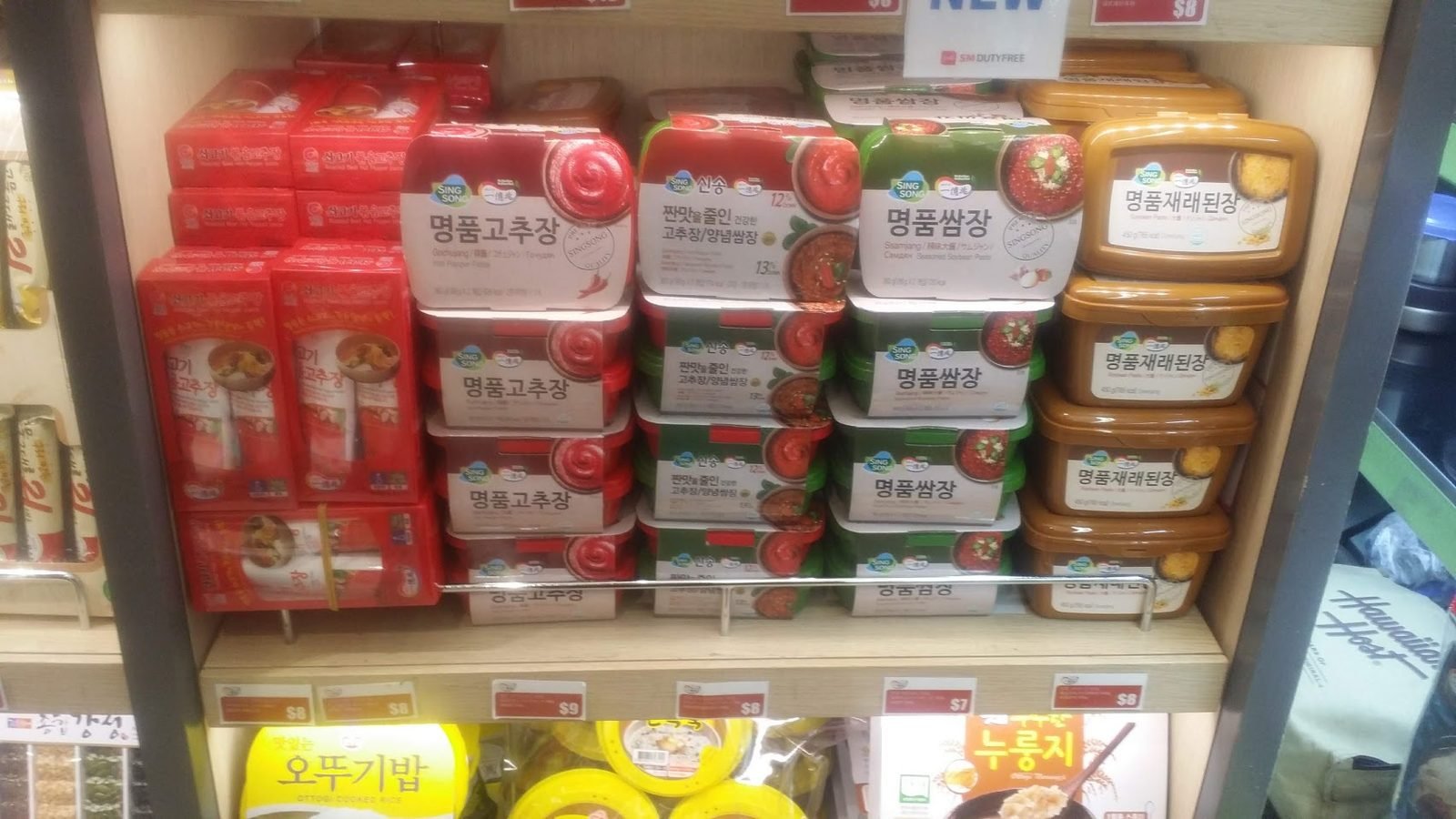 Shop shelf stacked with red gochujang tubs, green ssamjang tubs and brown doenjang tubs