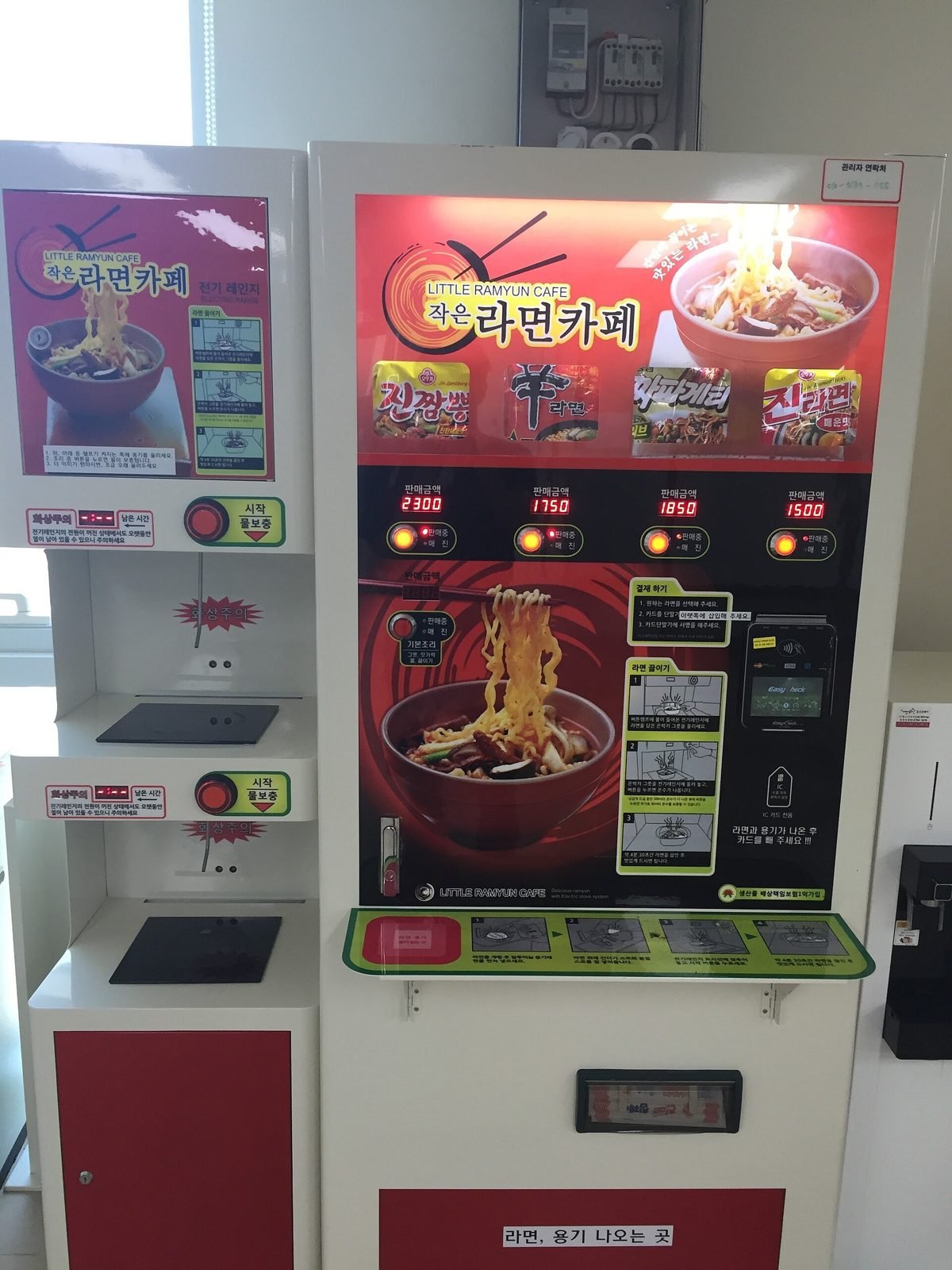 Red and white ramyeon vending machine in Korea with four packet choices and cooking plates beside it