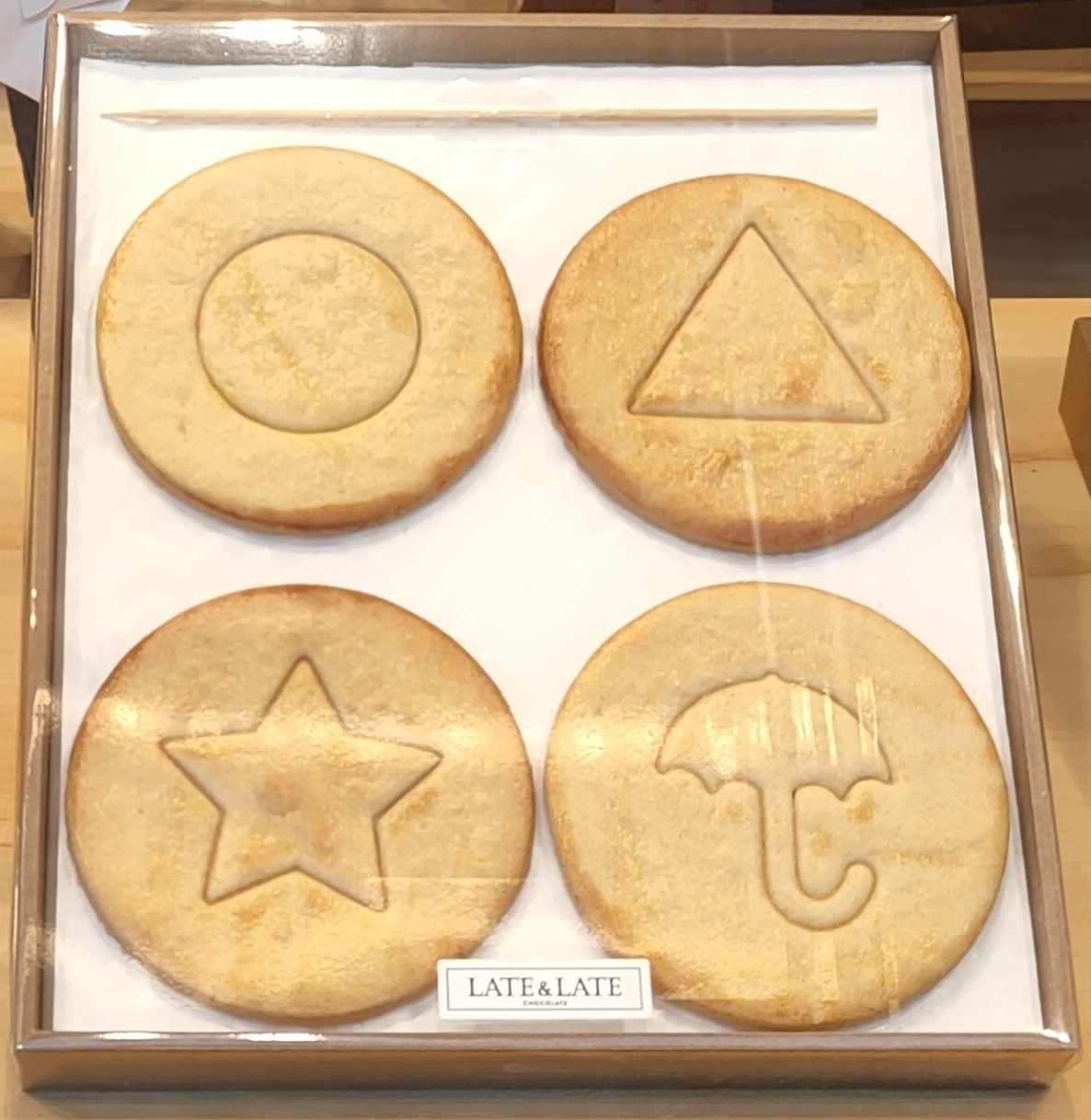 Four round honeycomb cookies stamped with a circle, triangle, star and umbrella